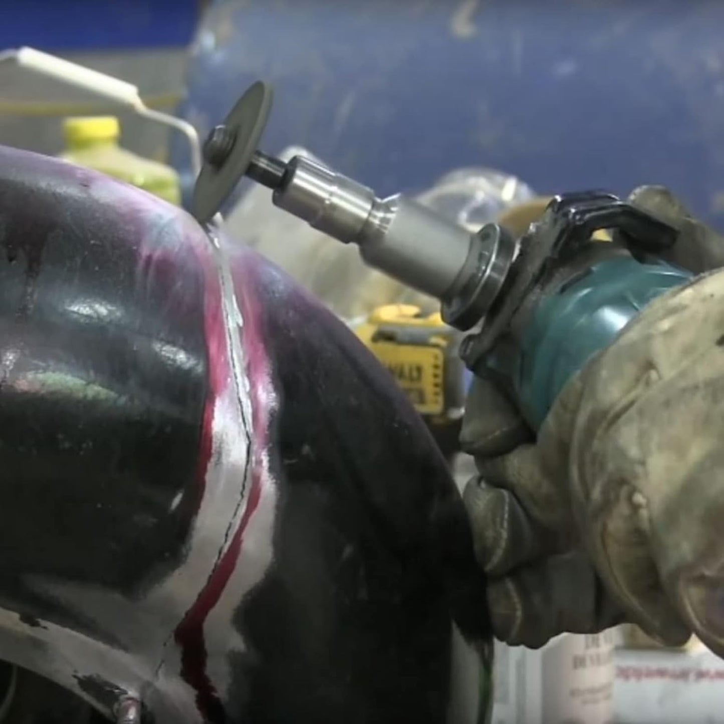 DRILAX flapper adapter on rotary grinder smoothing weld seam on curved metal tank by gloved hand